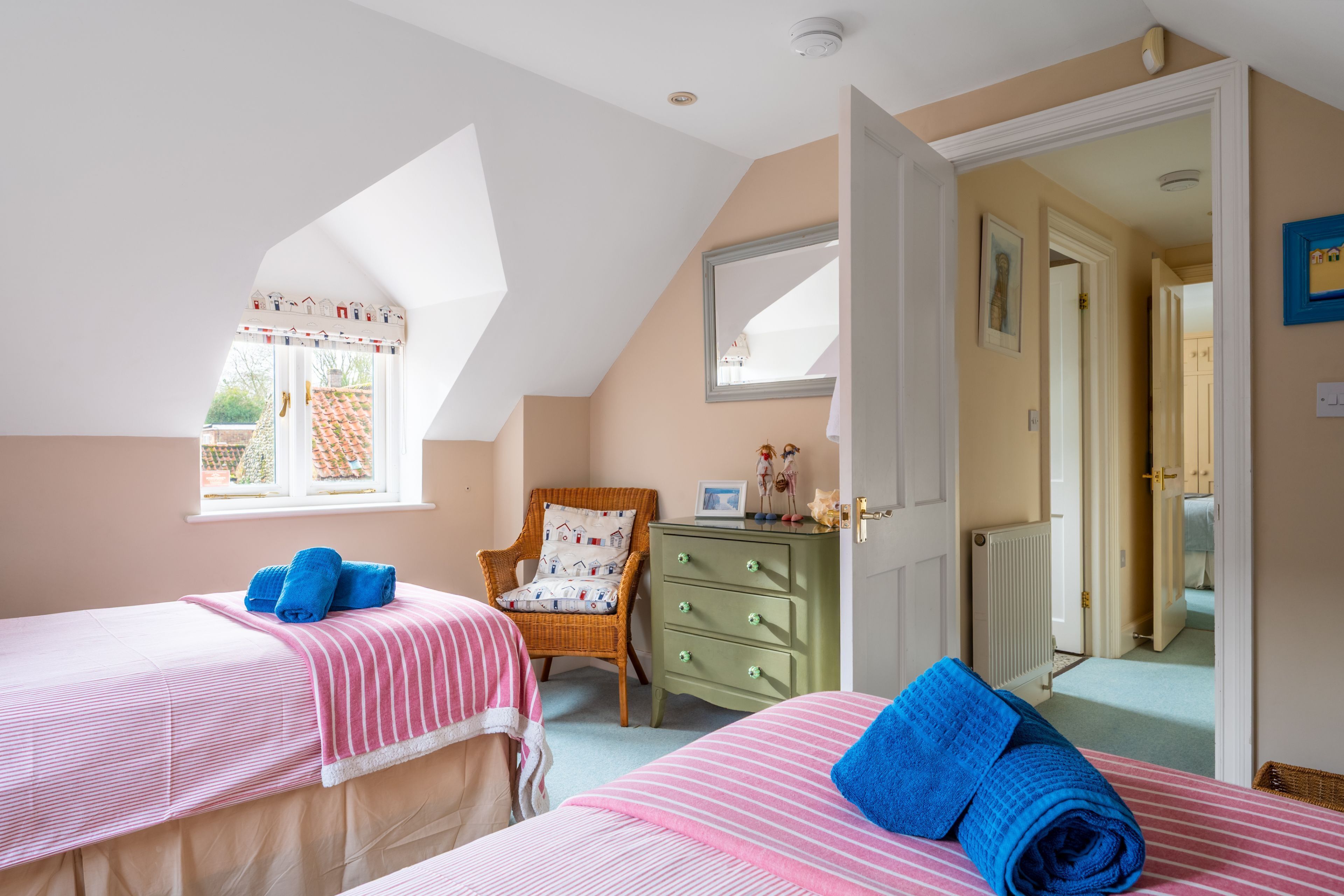 A bedroom with two beds, a chair, a dresser, and a window.