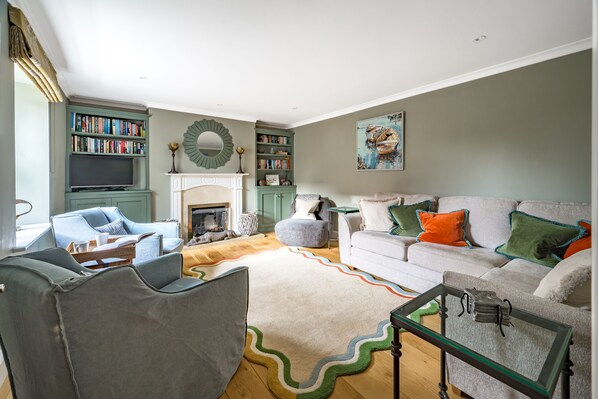 A living room with a fireplace, bookshelves, a sofa, and a coffee table.