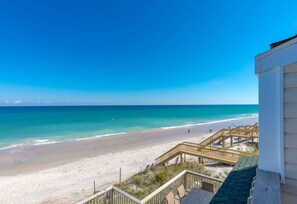 A beach view with a wooden walkway leading to a building.