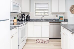 A kitchen with white cabinets, a microwave, a coffee maker, and a dishwasher.