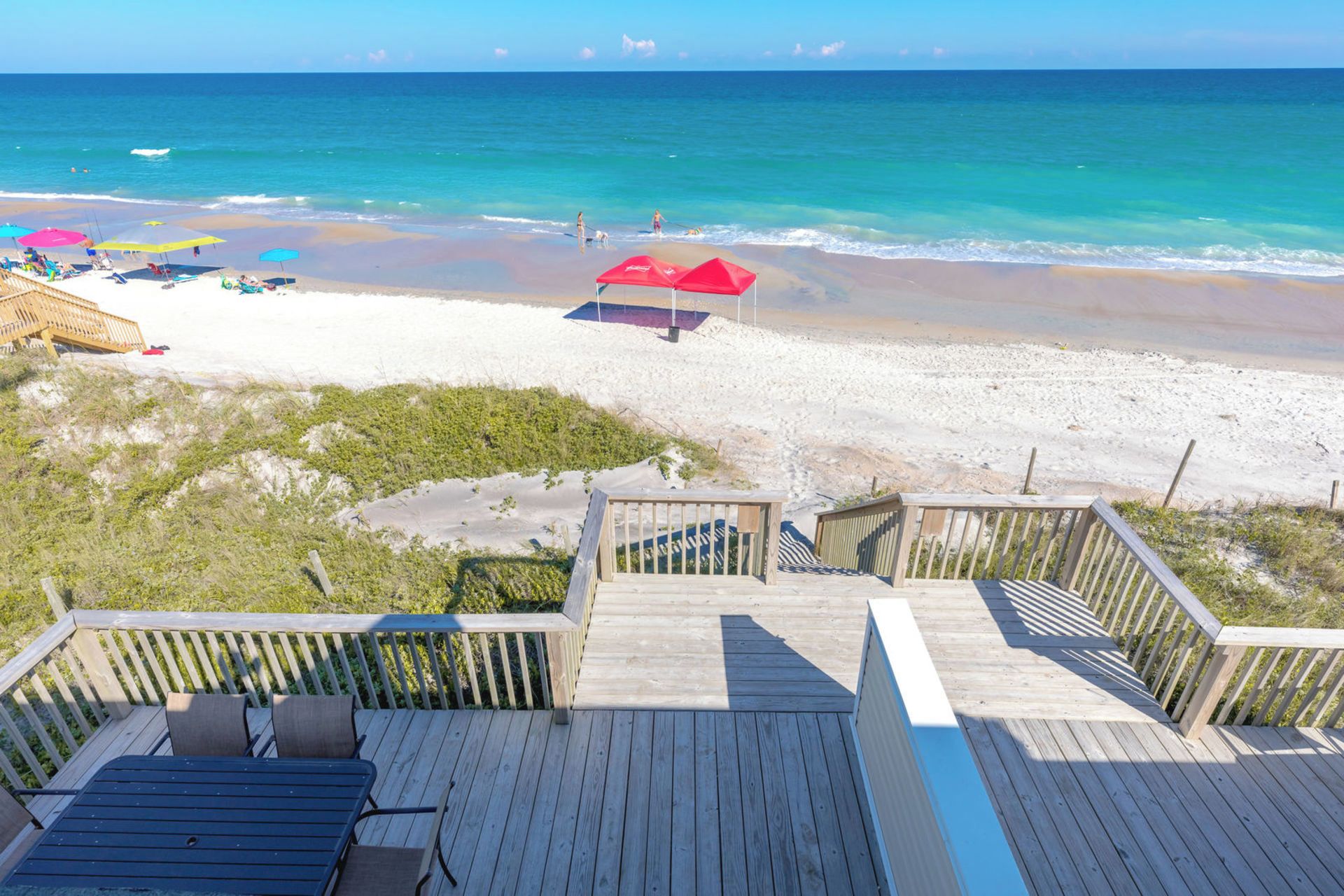 Une terrasse en bois offrant une vue sur une plage et l’océan.