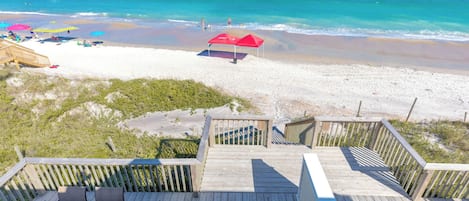Una terraza de madera con vista a una playa y al océano.