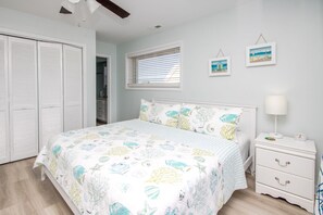 A bedroom with a bed, a nightstand, a dresser, a closet, and a window with blinds.