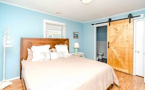 Cozy retreat with a large bed, nightstand, and framed picture, featuring a separate bathroom or storage area.