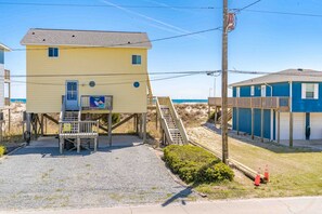 A two-story beach house with a staircase leading to a deck, a small outdoor seating area, and a view of the beach. - 75 Trips - 3BR 2nd Row Home - Covered Porch & Bonus Space; Dog Friendly! (Topsail Beach)