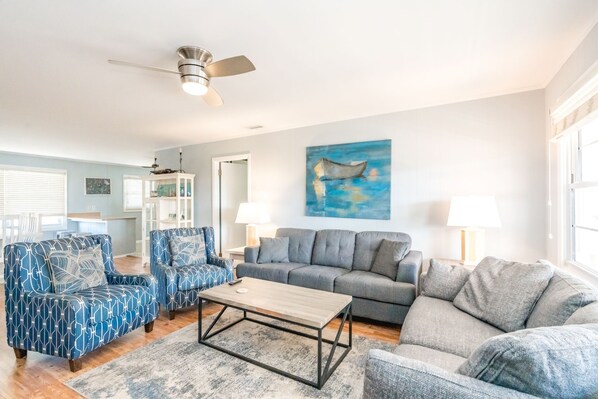 A living room with a ceiling fan, a painting, a sofa, a coffee table, and a chair.