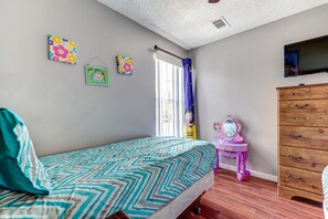A bedroom with a bed, dresser, vanity, and wall art.