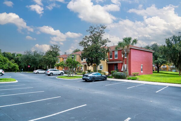 A residential street with houses, parked cars, and a clear sky.