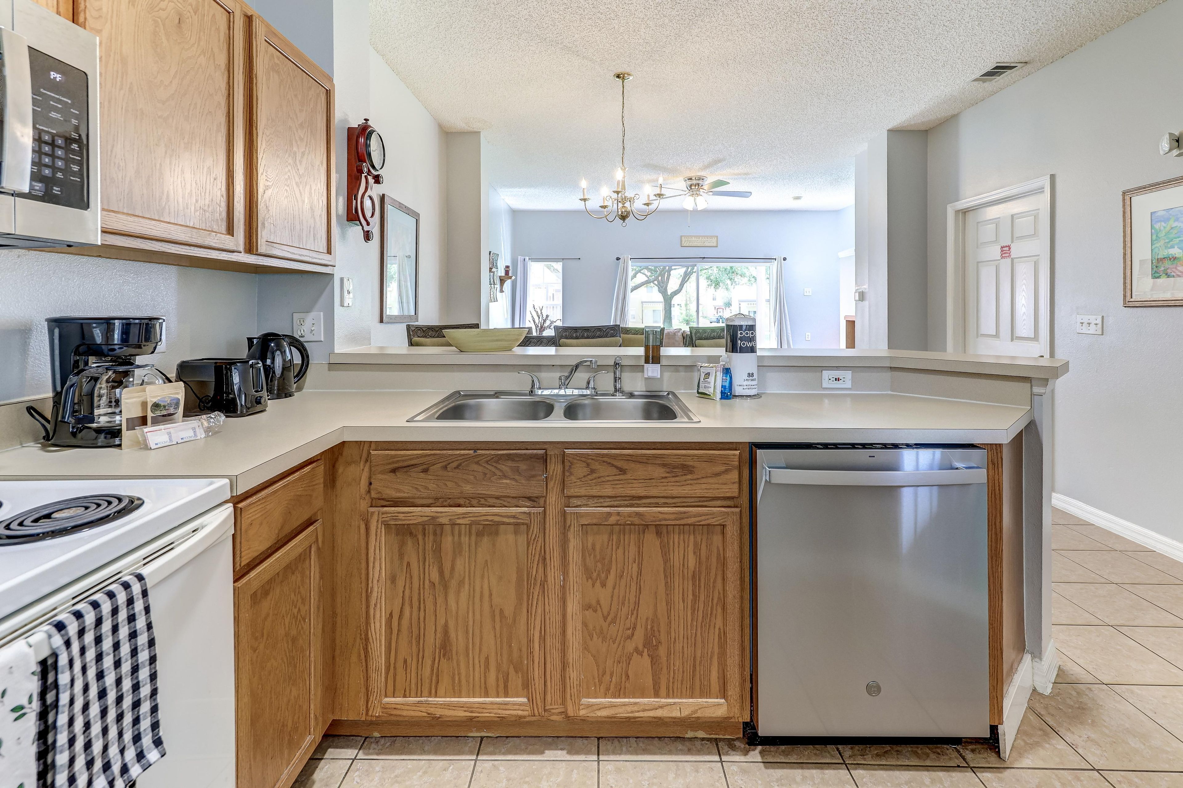 A modern kitchen with wooden cabinets, a stainless steel dishwasher, and a built-in oven.