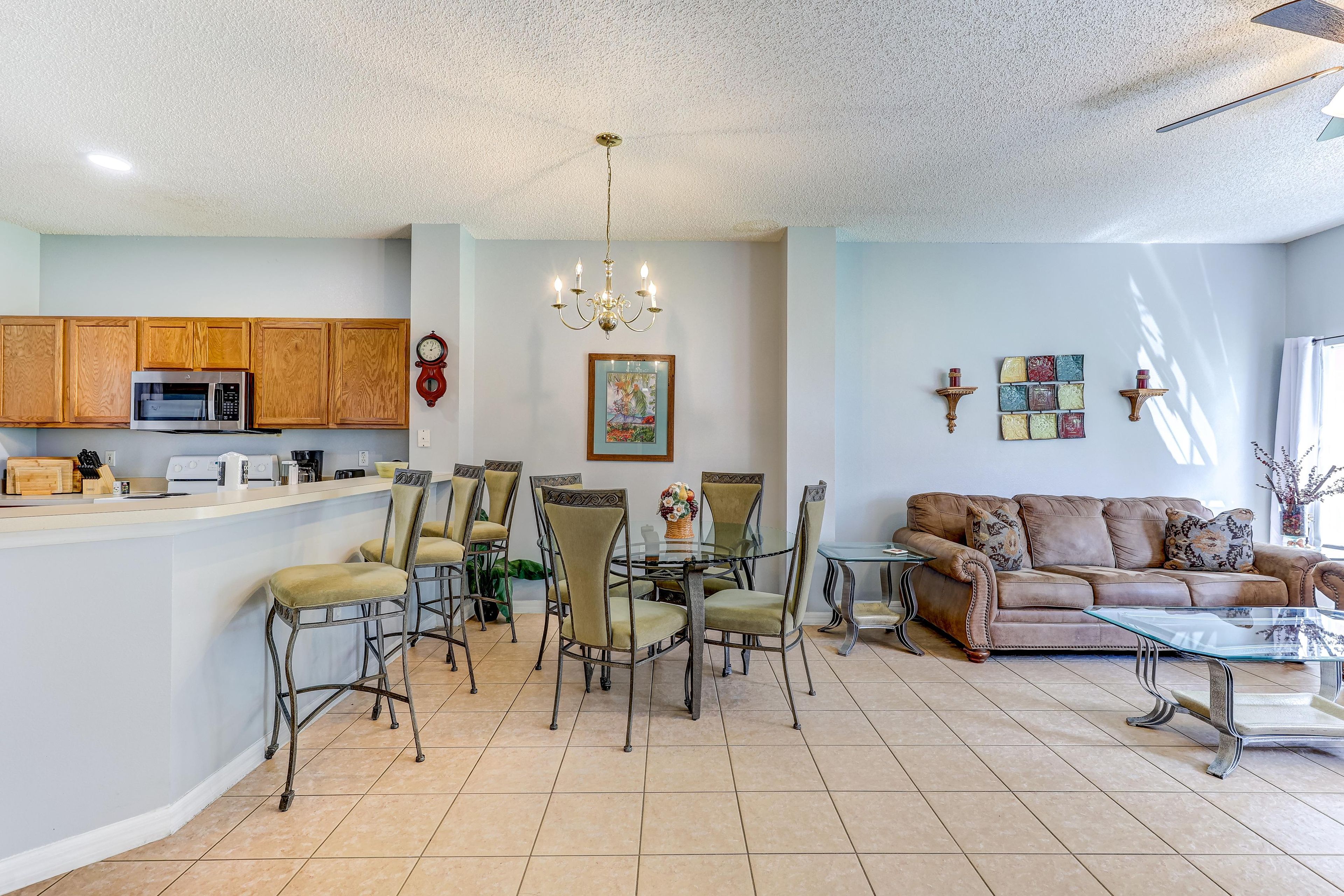 A spacious living area with a dining table, chairs, a sofa, and a kitchen area with wooden cabinets and appliances.