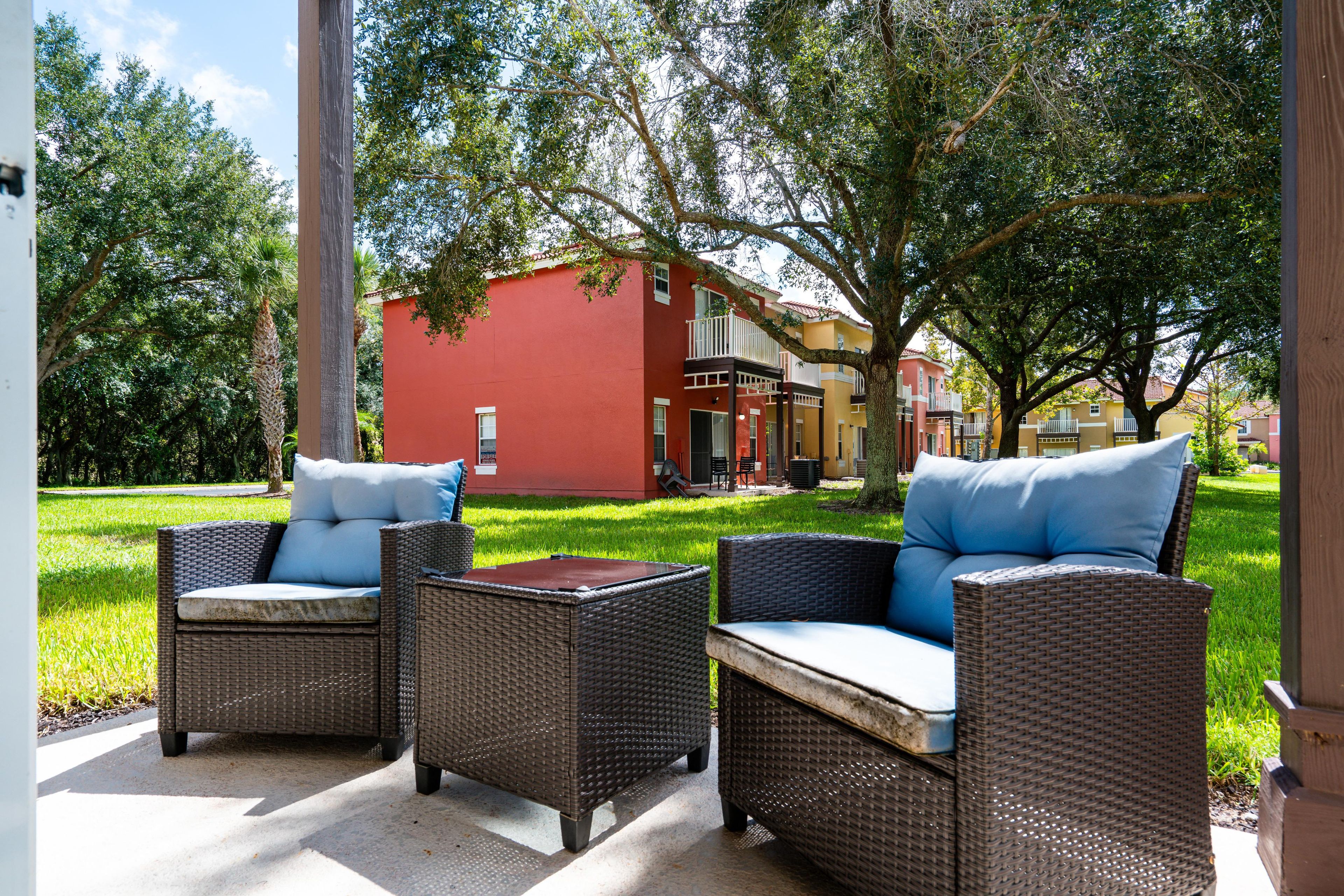 An outdoor seating area with wicker furniture and a red building in the background.