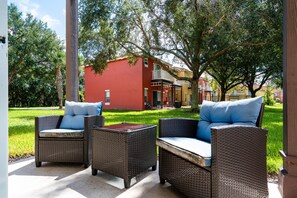 An outdoor seating area with wicker furniture and a red building in the background. - 3BR/2.5BA Blue Lagoon EI (Kissimmee)