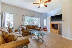 A living room with a sectional sofa, a glass coffee table, and a ceiling fan. - 3BR/2.5BA Blue Lagoon EI (Kissimmee)