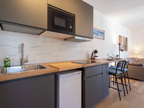A modern kitchen with a built-in microwave, stainless steel sink, and a compact dishwasher.