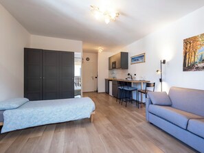 A compact living space with a kitchenette, a sofa, a bed, and a dining area.