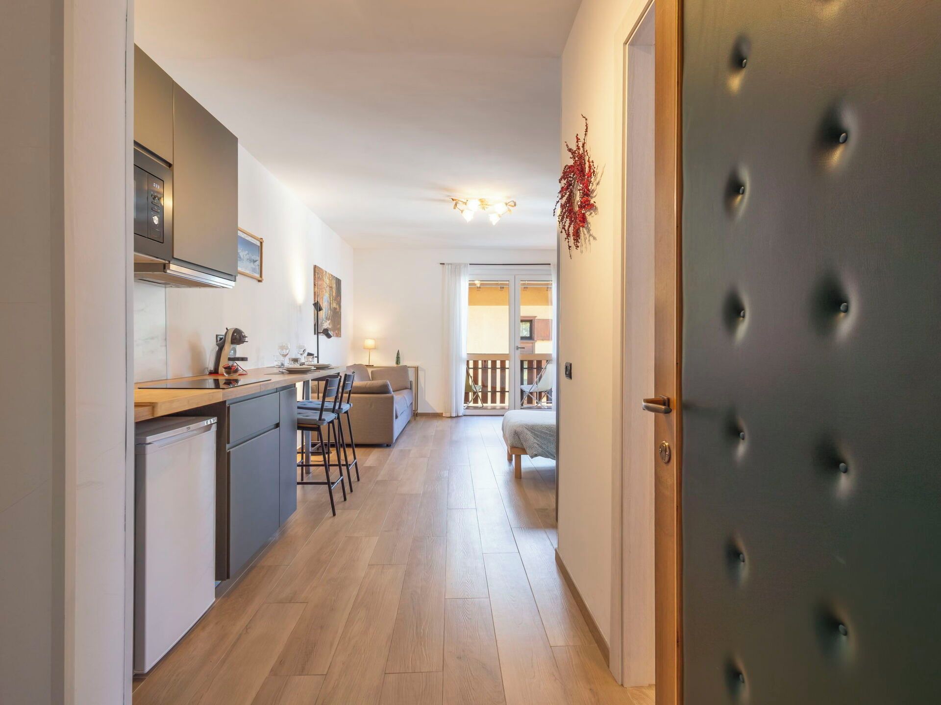 Een moderne keuken met een eethoek, een bank en uitzicht op een balkon.