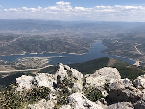 A mountainous landscape with rocky terrain and a view of a river and distant towns.