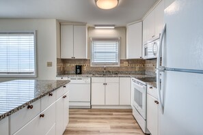 A kitchen with white cabinets, granite countertops, a built-in oven, and a microwave.