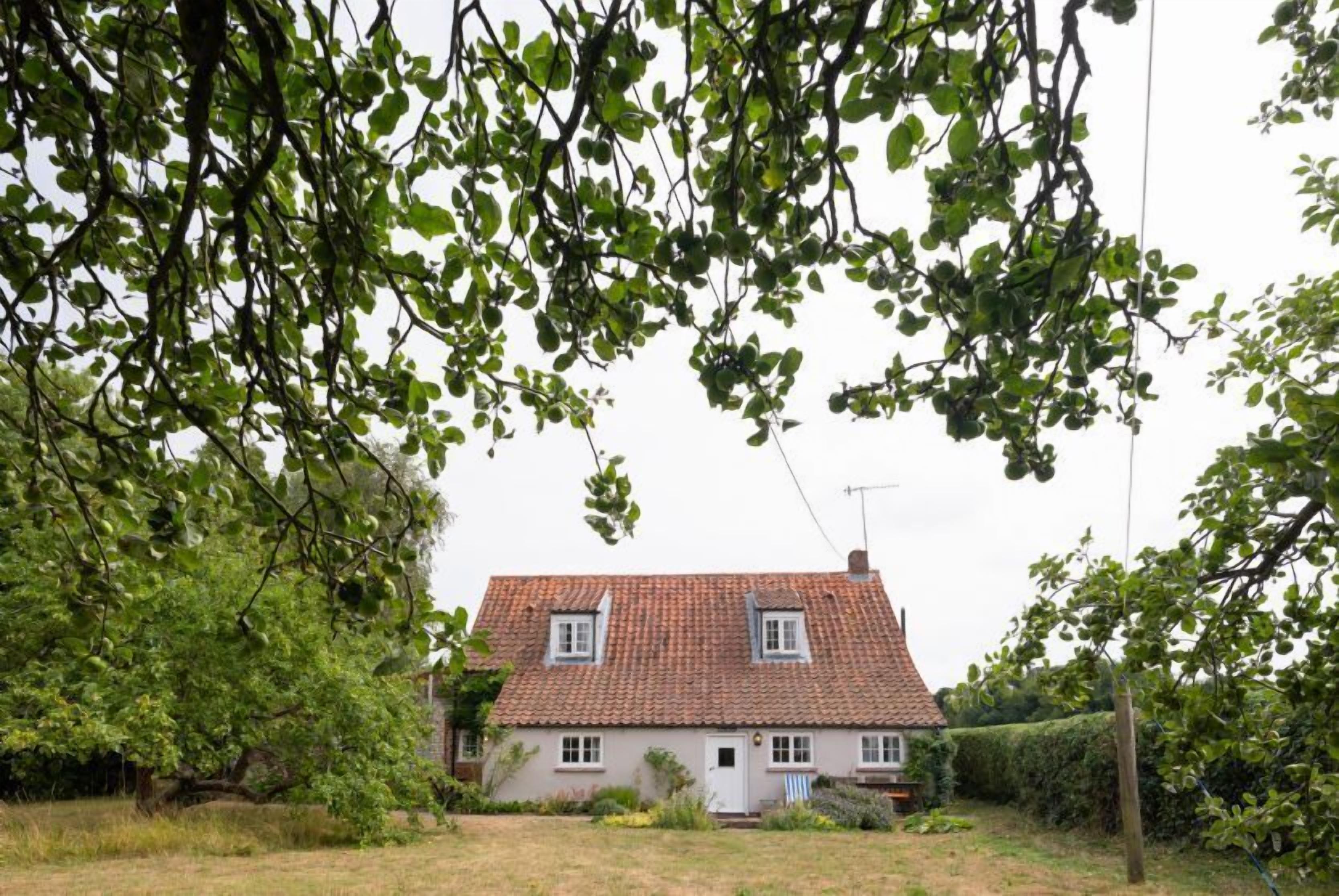 Ein Haus mit roten Ziegeln auf dem Dach, zwei Fenstern und einer weißen Tür.