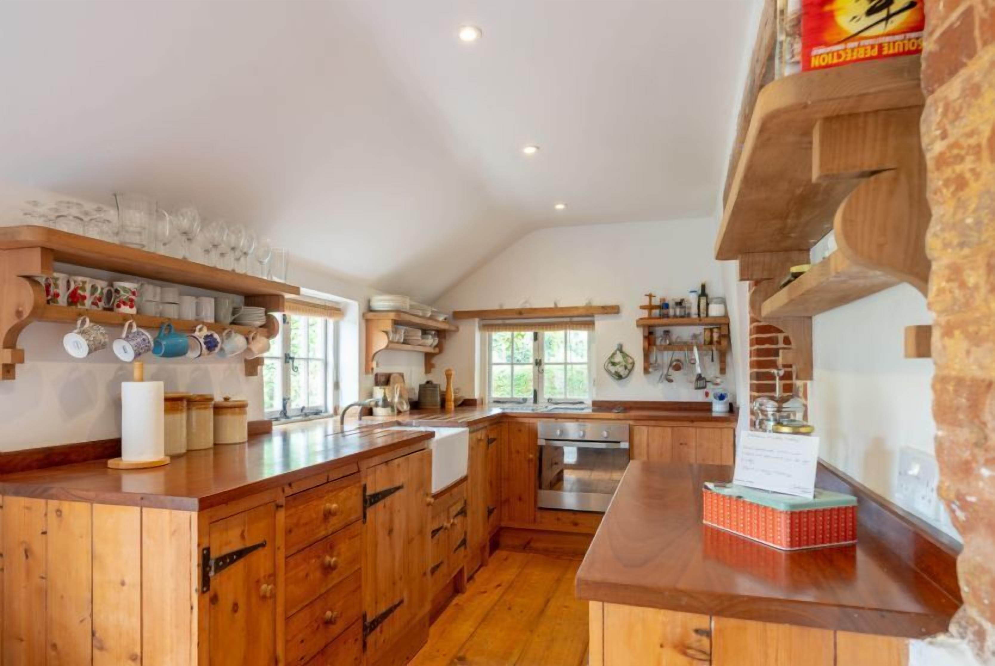 A spacious kitchen with wooden cabinets, a central island, and built-in shelves.