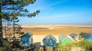 A beach with wooden walkways leading to beach huts. - Holly Cottage, Wells-next-the-Sea, Norfolk (Wells-Next-The-Sea)