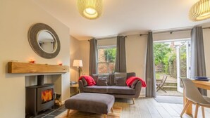 A cozy living room with a fireplace, a sofa, and a dining area. - Holly Cottage, Wells-next-the-Sea, Norfolk (Wells-Next-The-Sea)