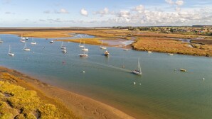 Een kustgebied met boten op rustig water, een zandstrand en een afgelegen dorp.