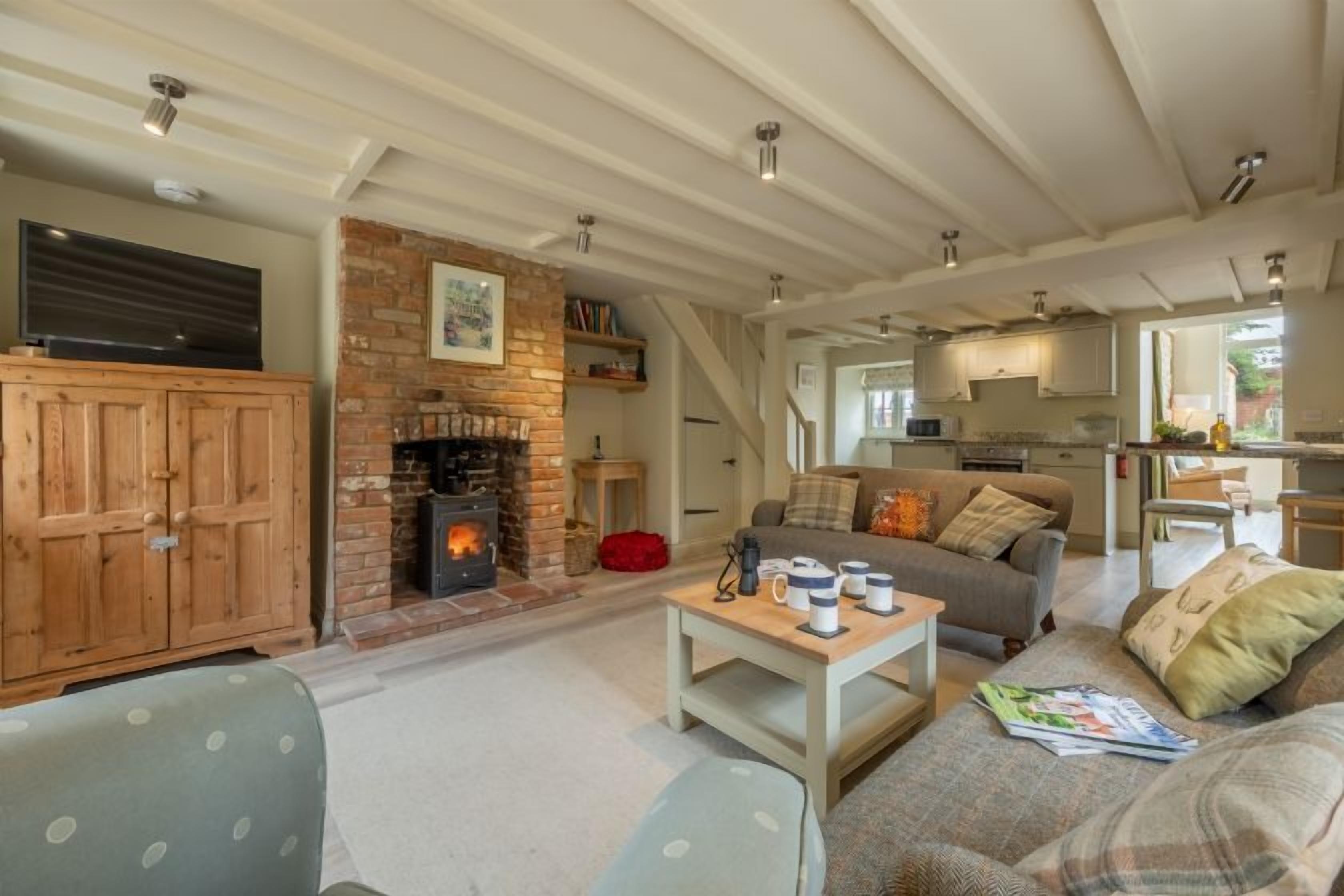 Una sala de estar acogedora con chimenea, un sofá, una mesa de centro y un televisor.