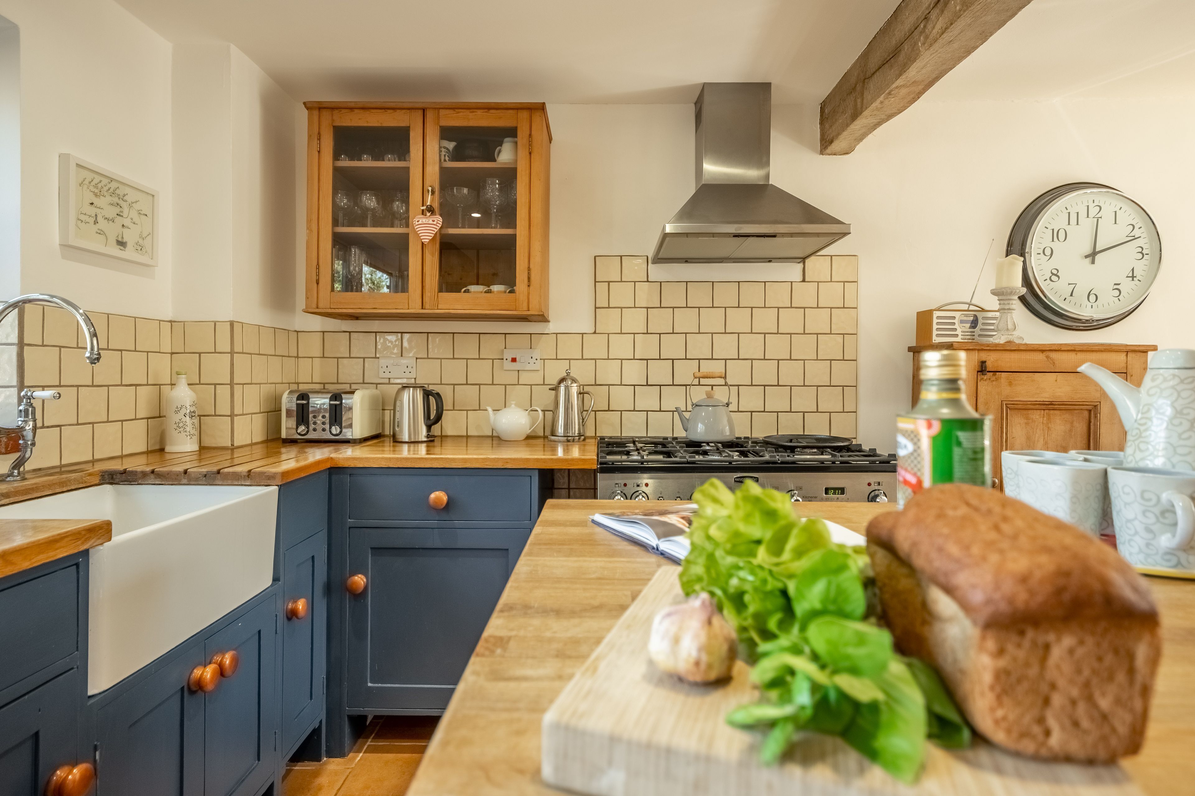 A kitchen with a stove, cabinets, and a clock.