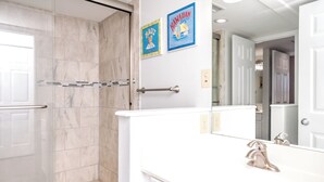 Une salle de bain avec une douche, des toilettes et un lavabo. Deux tableaux encadrés sont accrochés au mur.