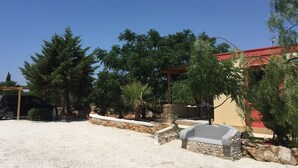 Zona residencial con una casa, un automóvil y varios árboles.