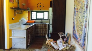 Una cocina funcional con estufa a gas, lavamanos y un reloj en la pared.