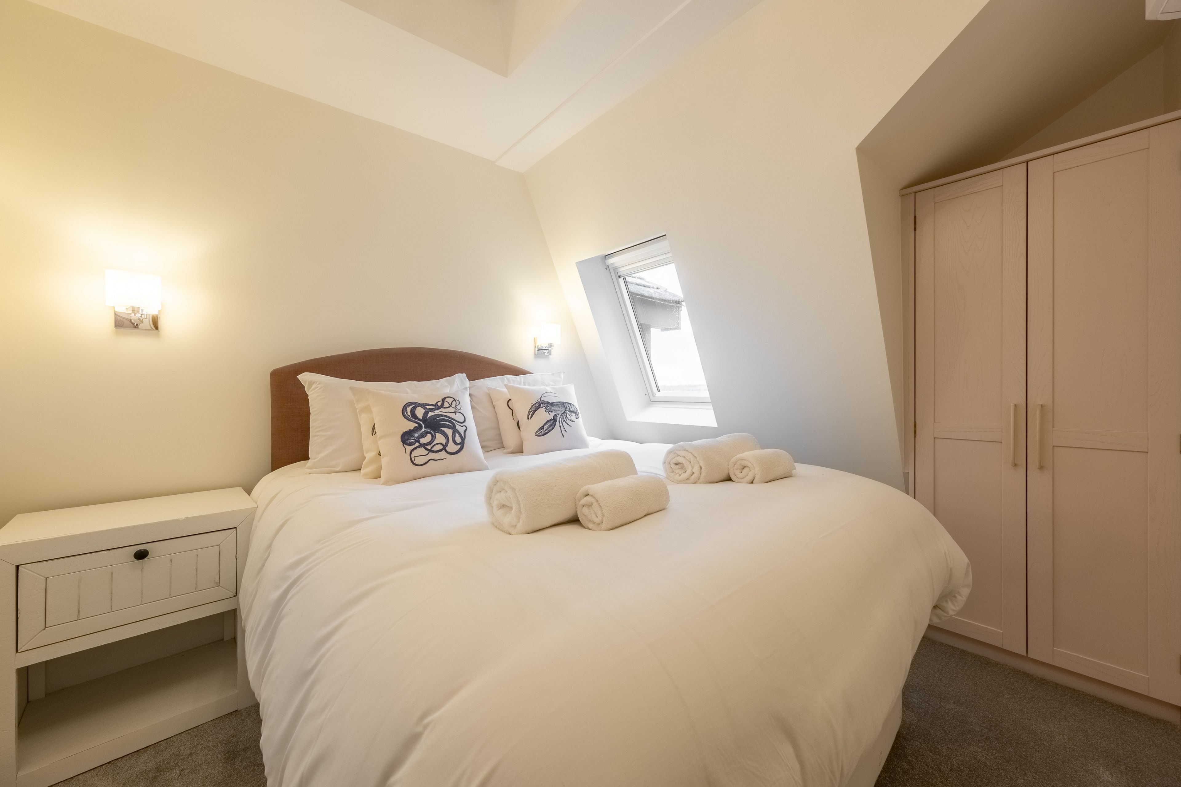 A bedroom with a bed, bedside tables, a wardrobe, and a window with natural light.