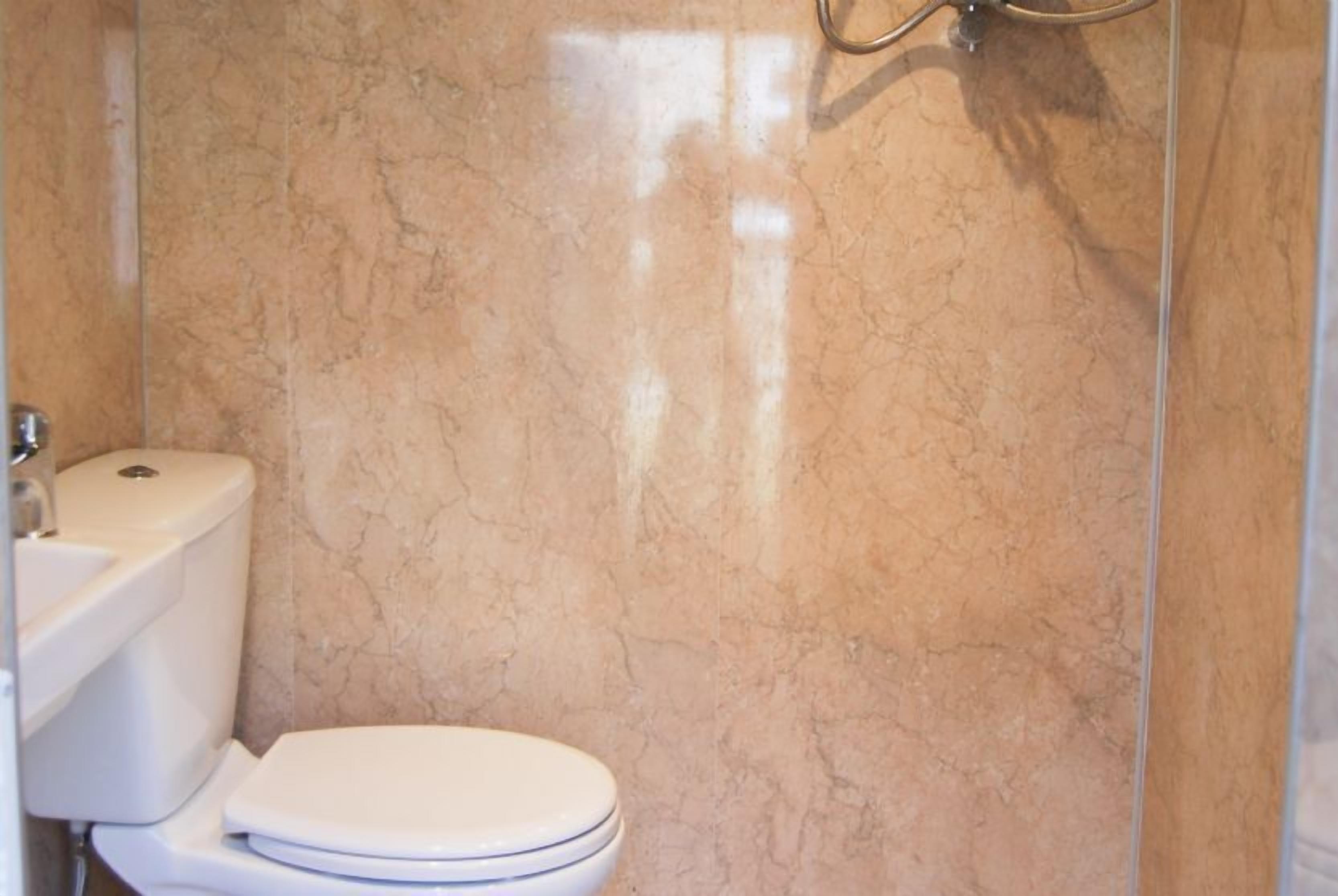 Une salle de bain comprenant des toilettes, un lavabo et un espace douche.