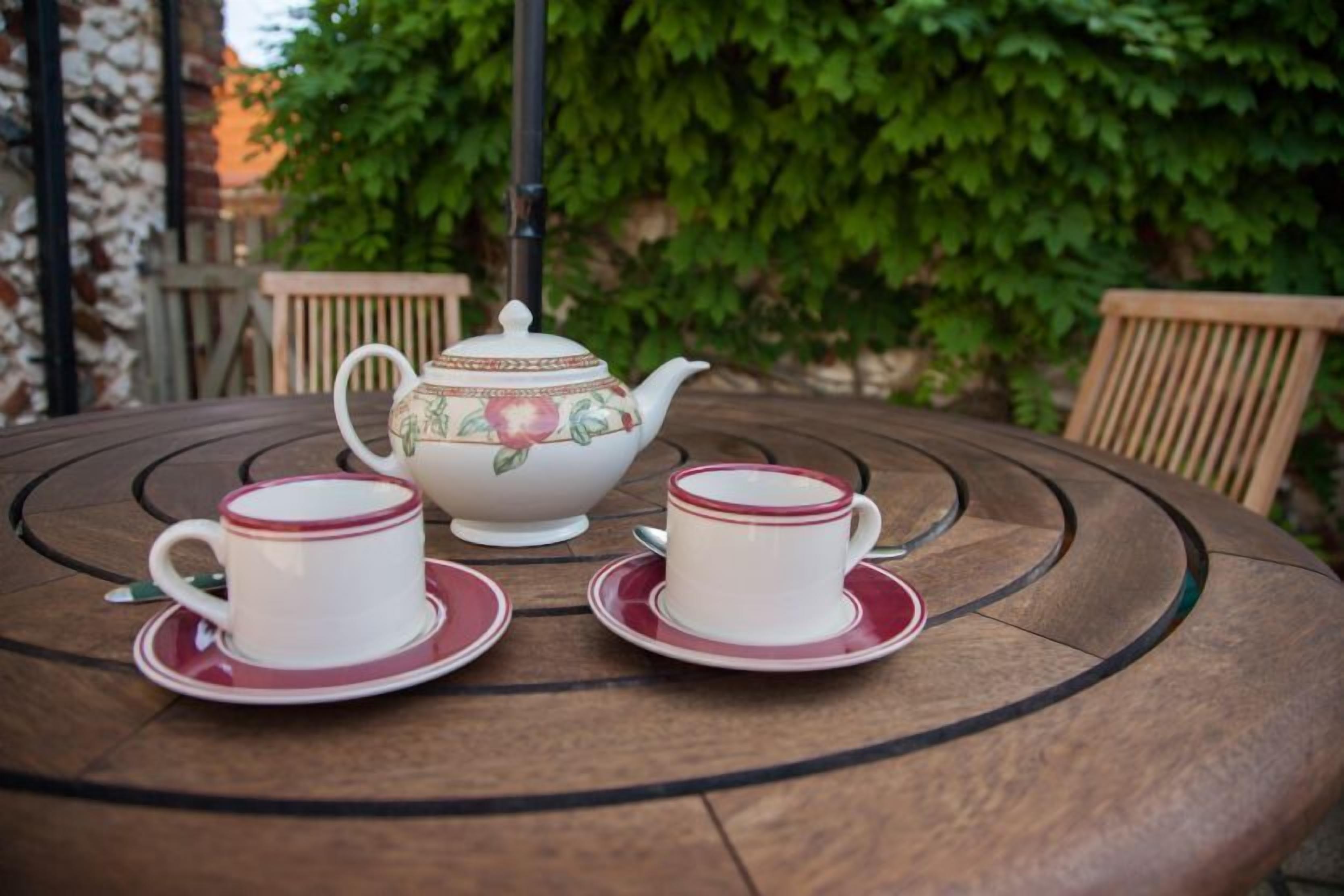 Une table ronde avec une théière et deux tasses sur des soucoupes.