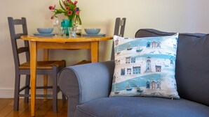 Un comedor con una mesa de madera, sillas y un cojín azul estampado con motivos marinos.