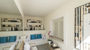 A modern, well-lit room with a seating area, a glass coffee table, and a large mirror. - Villaggio S'abba e Sa Pedra - S'ABBA 22 (07020 Golfo Aranci OT)