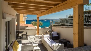 A covered outdoor seating area with a view of the sea and mountains. - Villaggio S'abba e Sa Pedra - S'ABBA 22 (07020 Golfo Aranci OT)
