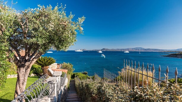 A coastal pathway leading to a view of the sea with boats and distant mountains. - Villaggio S'abba e Sa Pedra - S'ABBA 22 (07020 Golfo Aranci OT)