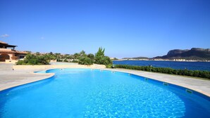 Une piscine offrant une vue dégagée sur la mer et les montagnes lointaines.