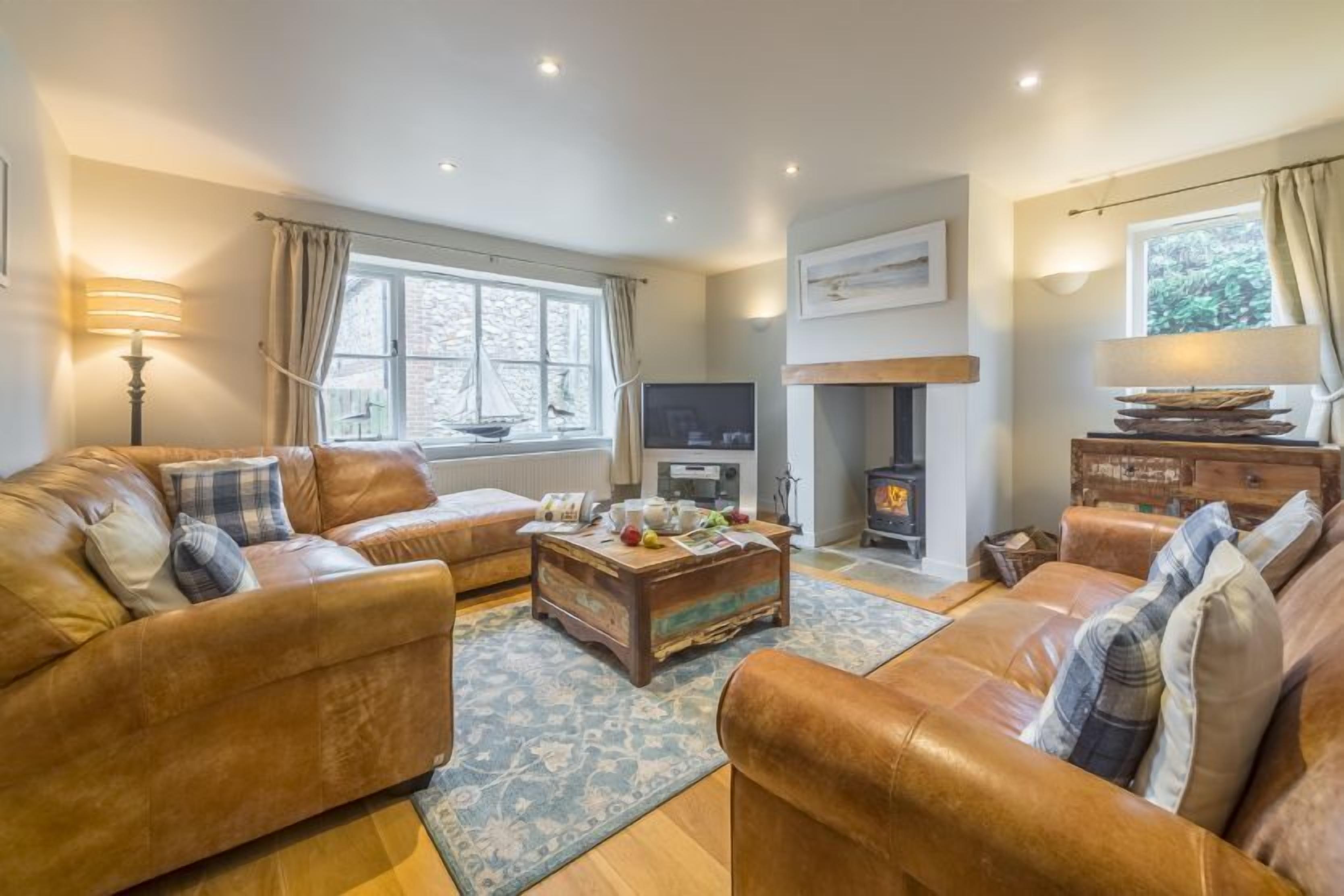 A cozy living room with leather sofas, a wooden coffee table, a fireplace, and a television.