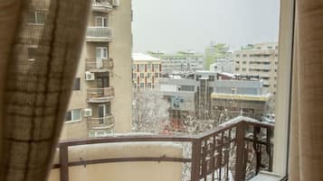 Udsigt fra en balkon med gelænder, der kigger ud over et boligområde med flere bygninger og en klar himmel.