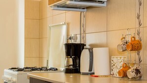 A kitchen with a gas stove, a coffee maker, and a coffee cup rack with branded mugs. - Motru 84 by MRG Apartments | Central | Balcony | Metro | Park & Amenities (București)