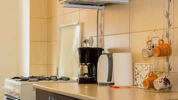 Eine Küche mit einem Gasherd, einer Kaffeemaschine und einem Kaffeetassenhalter mit beschrifteten Tassen.