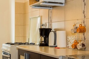 Eine Küche mit einem Gasherd, einer Kaffeemaschine und einem Kaffeetassenhalter mit beschrifteten Tassen.