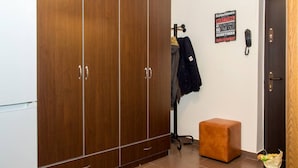 A room with a wardrobe, a coat rack, a telephone, and a small stool. - Motru 84 by MRG Apartments | Central | Balcony | Metro | Park & Amenities (București)