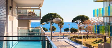 Un edificio moderno con balcón de cristal con vistas a la playa.