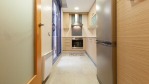 A narrow kitchen with a built-in oven, a stainless steel range hood, and a small countertop. - Apartment in Family Complex 50m beach · UHC MAR AUGUSTA 212 (Cambrils)