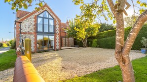 Une maison moderne dotée d’une grande fenêtre et d’une allée gravillonnée.