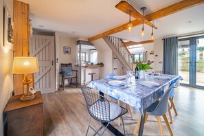 A dining area with a table set for four, a staircase, and a view of the outdoors. - Plumtrees, Thornham, Norfolk (Thornham)